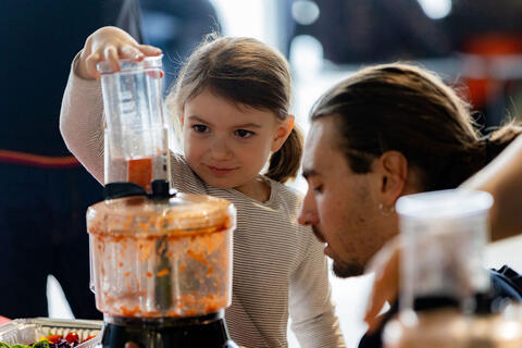 un adulte aide un enfant à cuisiner